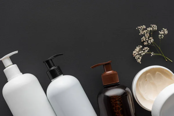 Top view of bottles of cream and dried flowers isolated on black, beauty concept — Stock Image Top View Bottles Cream Dried Flowers Isolated Black Beauty Concept Stock Image