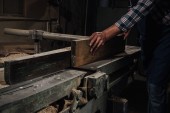 Oříznout záběr tesaře pracujícího se dřevem v dílně