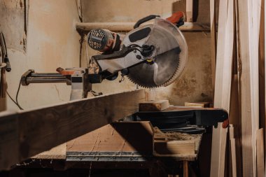 close up view of circular saw and wooden planks at wooden workshop clipart