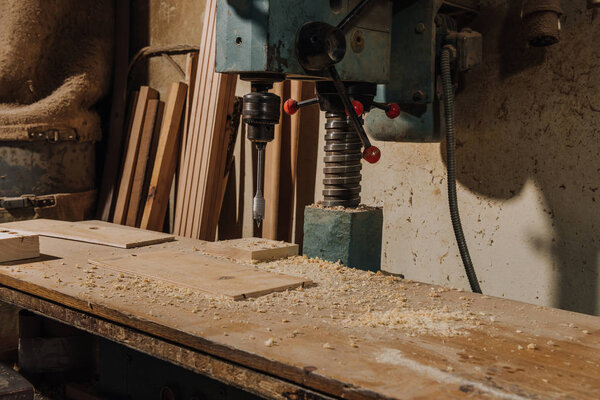 close up view of electric drill and wood at wooden carpentry workshop