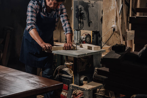 partial view of woodworker using electric drill on wood at workshop