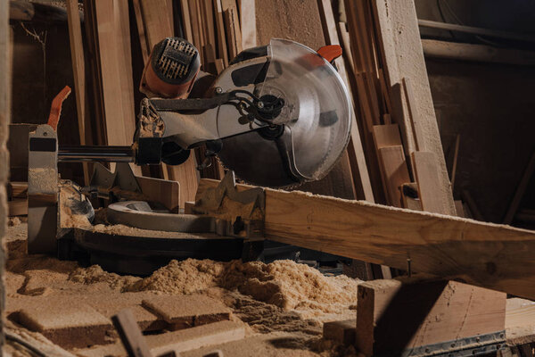 close up view of circular saw and wooden planks at wooden workshop