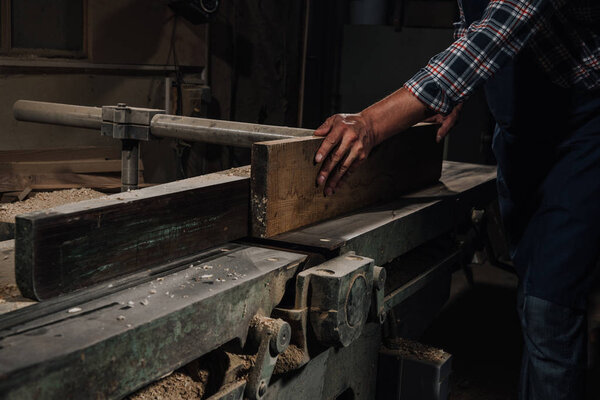 cropped shot of carpenter working with wood at workshop