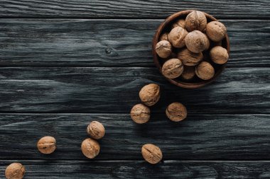 delicious walnuts in wooden bowl on dark wooden tabletop clipart