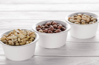 Beyaz ahşap masa üzerinde seramik kase lezzetli fındık