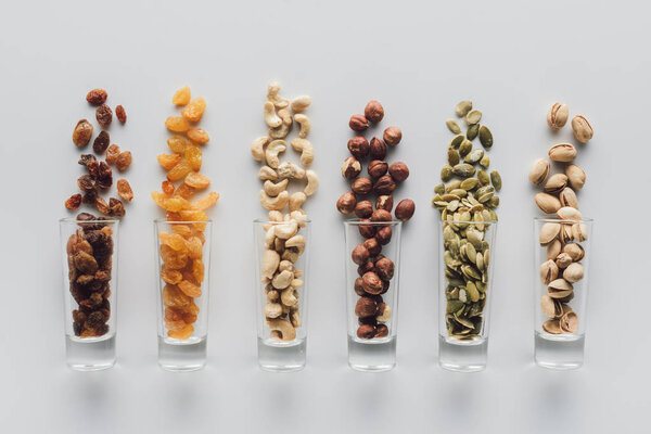 Ассорти вкусные орехи и изюм в стеклянных чашках изолированы на белом фоне
