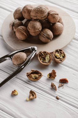 delicious walnuts with metal nutcracker on wooden table clipart