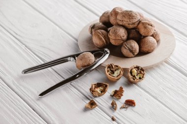 walnuts with metal nutcracker on wooden background clipart