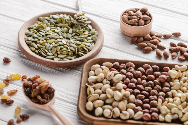 Assorted delicious nuts and raisins in wooden plates and spoon