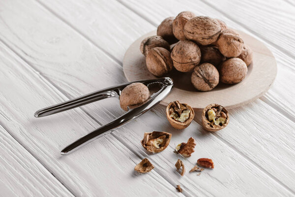 walnuts with metal nutcracker on wooden background