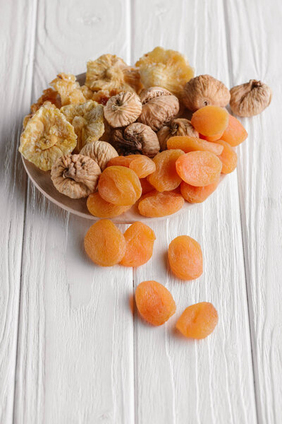 Variety of dried fruits on white plate on wooden surface