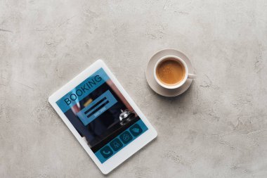 fincan kahve ve tablet rezervasyon uygulaması ile üstten görünüm üstünde perde beton yüzeyi