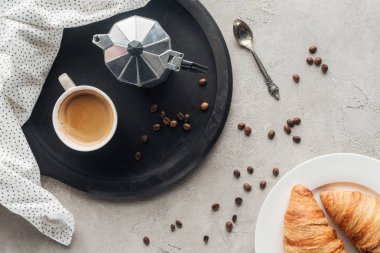 fincan kahve ve moka pot üstten görünüm dökülen kahve çekirdekleri ve kruvasan tabak ile beton yüzeyi