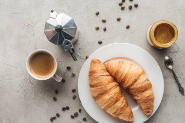 kruvasan ve moka pot ile lezzetli kahve üstten görünüm dökülen kahve çekirdekleri ile beton yüzeyi