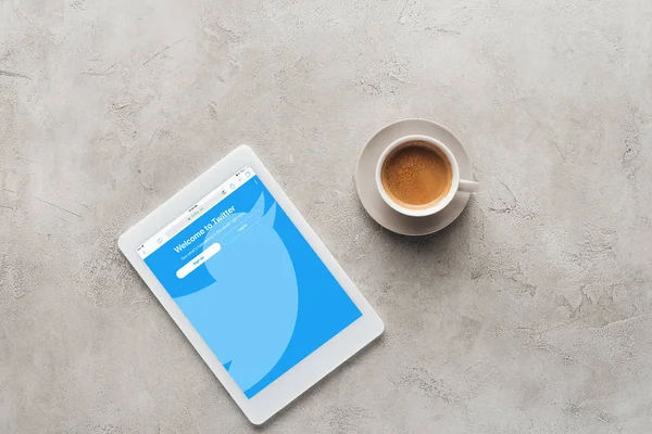 コンクリート表面画面で一杯のコーヒーと Twitter のウェブサイトでタブレットのトップ ビュー — ストック写真