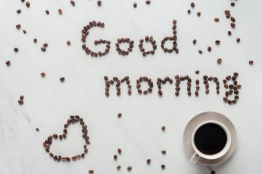 beyaz mermer üzerinde kahve çekirdekleri fincan kahve ve Günaydın yazı üstten görünüm yapılmış