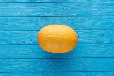 top view of whole ripe yellow melon on blue wooden surface   clipart