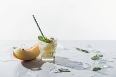 close-up view of summer drink with melon and mint in glass and slice of sweet melon with ice cubes on white clipart