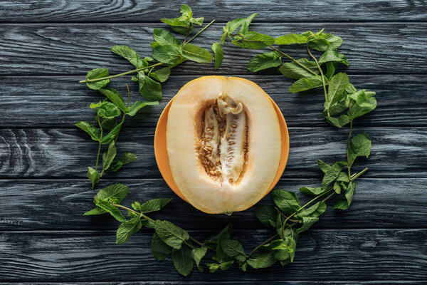 top view of fresh ripe sweet melon and fresh mint on wooden surface