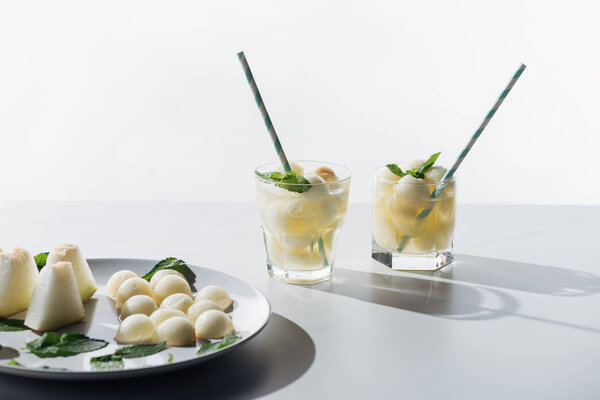 sweet melon balls and refreshing beverage with melon and mint in glasses on white 