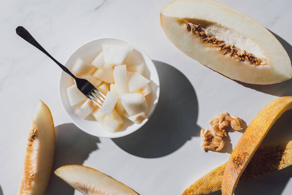 top view of sweet ripe sliced melon and seeds on white  