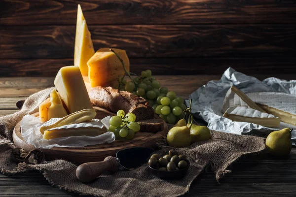 さまざまな種類のチーズ ぶどうと梨のテーブルの上 — ストック写真