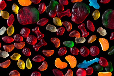 top view of different colored jelly candies isolated on black clipart