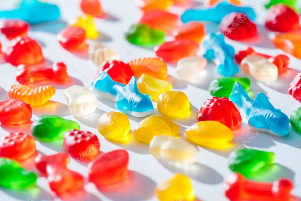 Different colored jelly candies on white surface