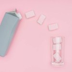 Top view of marshmallows, glass and carton package isolated on pink