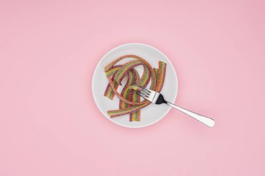 düz renkli jöle şekerler şeker ve çatal ile üstten görünüm pink izole plaka üzerinde
