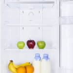 Rijpe smakelijke vruchten en flessen van melk in de koelkast