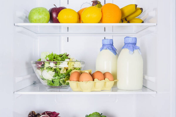 oranges, apples, eggs and milk in bottles in fridge