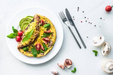 düz lay ev yapımı omlet kiraz domates, avokado parçaları, ıspanak ve beyaz mermer yüzeyi ile