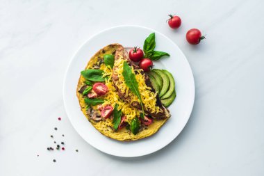 kiraz domates, avokado parçalar ve ıspanak ile ev yapımı omlet üstten görünüm beyaz mermer yüzeyi
