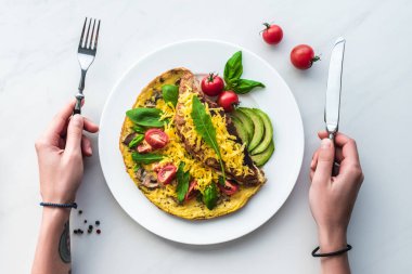 kadının kahvaltıda ev yapımı omlet ile masa üstü, elinde çatal ile kısmi görünümü