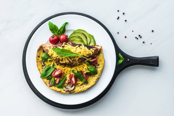 food composition with healthy omelette on wooden board on white marble tabletop