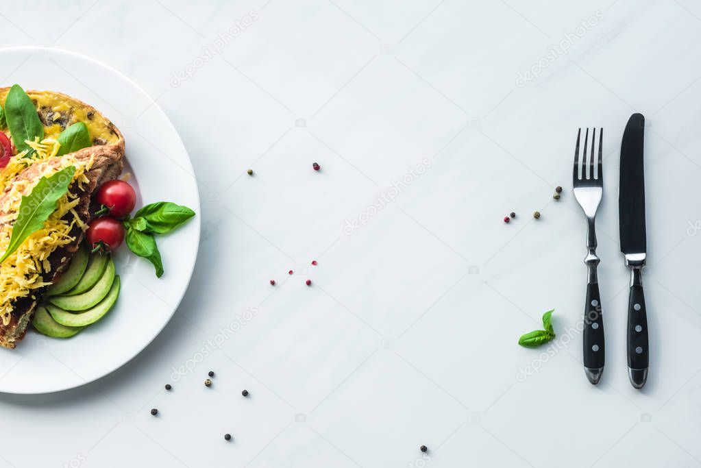 top view of healthy omelette for breakfast and cutlery on white marble surface