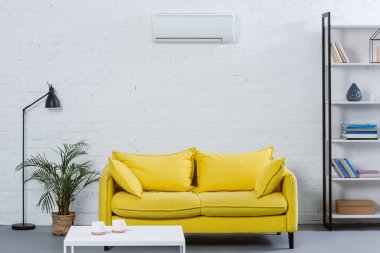 Sarı kanepe ve klima beyaz duvarda asılı modern oturma odası iç
