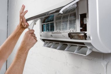 cropped shot of repairman taking off filter from conditioner clipart