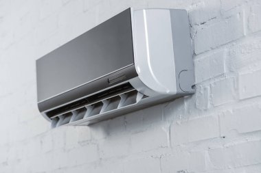 close-up shot of modern air conditioner hanging on white brick wall clipart