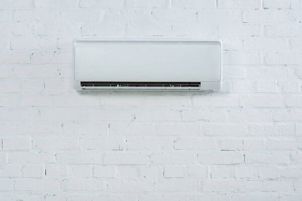 front view of air conditioner hanging on white brick wall