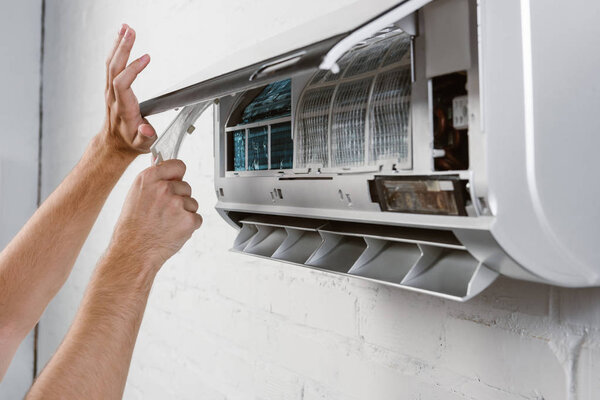 cropped shot of repairman taking off filter from conditioner