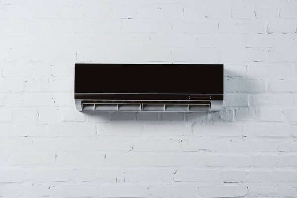 modern air conditioner hanging on white brick wall