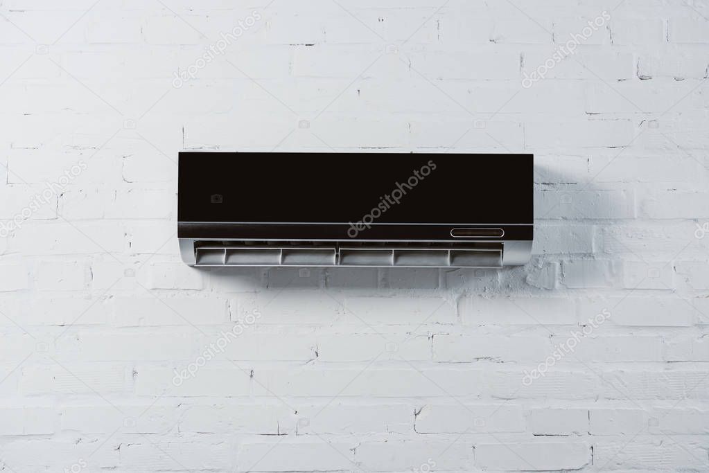 Modern air conditioner hanging on white brick wall