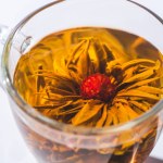 Primer plano de té de hierbas con flor en vidrio
