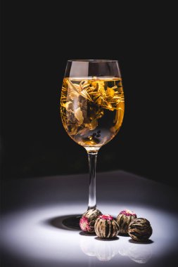 glass of traditional chinese flowering tea with tea balls on table isolated on black clipart
