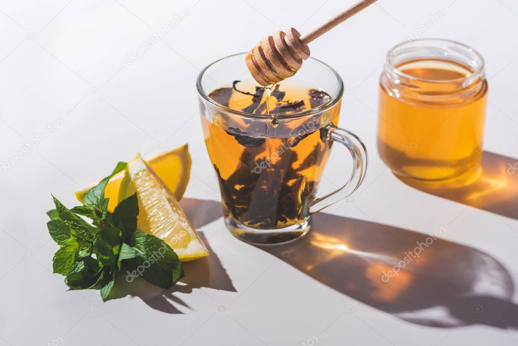 healthy tea with honey, lemon and mint on white tabletop