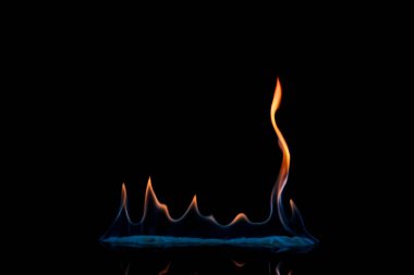 close up view of small burning orange and blue flame on black background clipart