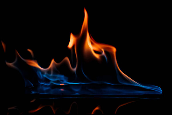 close up view of burning orange and blue flame on black background
