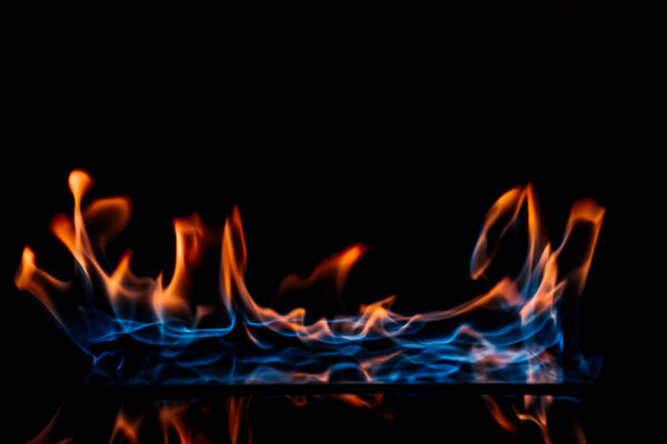 close up view of burning orange and blue flame on black background